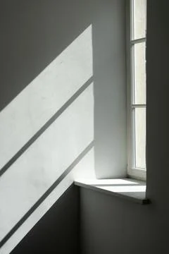 Sunlight and window shadow projection on a blank white wall in an empty room Stock Photos