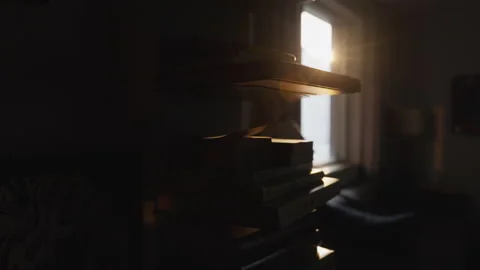 Sunlight Beaming Through Window Into Dark Room with Books Stock Footage 337534017