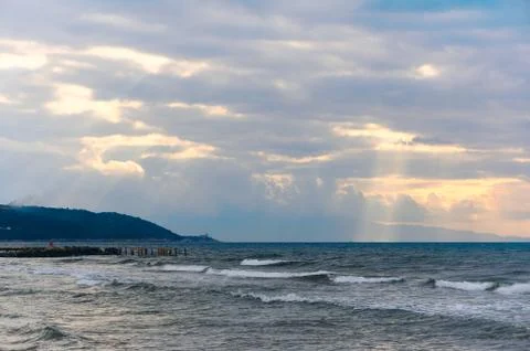 Sunlight beams through the clouds on the beach in a winter day Stock Photos