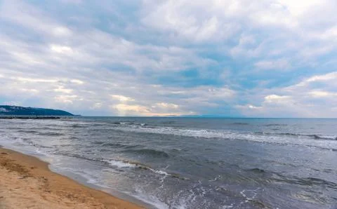 Sunlight beams through the clouds on the beach in a winter day 写真素材
