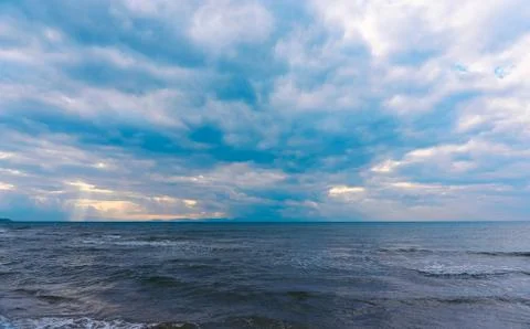 Sunlight beams through the clouds on the beach in a winter day Stock Photos