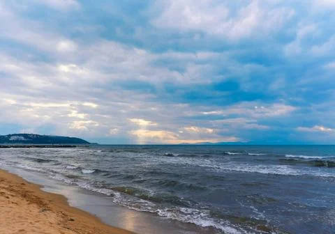 Sunlight beams through the clouds on the beach in a winter day Stock Photos