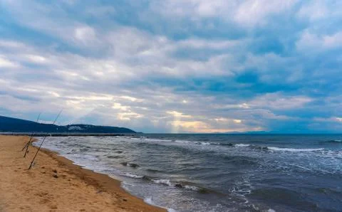 Sunlight beams through the clouds on the beach in a winter day Stock Photos