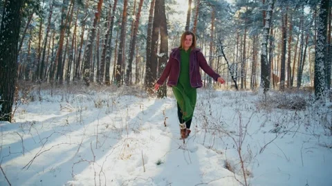 Sunlight beams through winter forest as woman walks with open arms Stock Footage 342782659