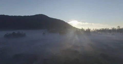 Sunlight behind the mountains with thick fog in the morning Stock Footage 296265173