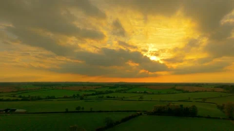 Sunlight breaking through clouds over green agricultural landscape during Stock Footage 323591681