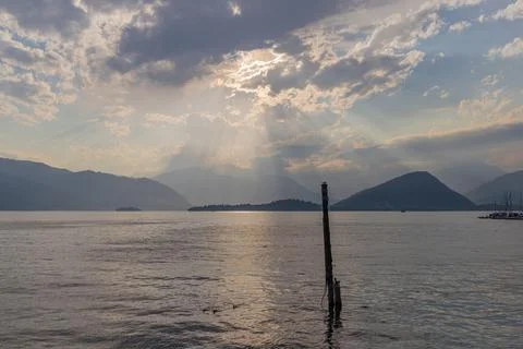 Sunlight Breaking Through Clouds Over A Peaceful Mountain Lake View Stock Photos