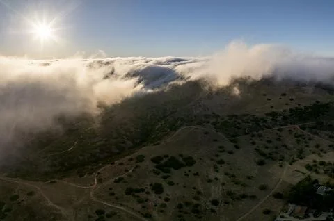 Sunlight breaking through clouds over rolling hills and winding paths Fotos de archivo