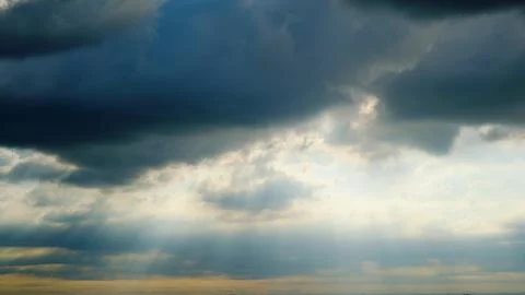 Sunlight breaking through dark storm clouds in the sky. Dramatic weather scen Stock Photos
