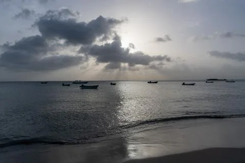 Sunlight breaking through dramatic clouds above anchored boats at Manchineel Bay Photos