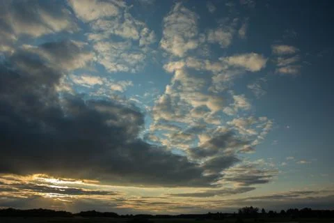 Sunlight breaking through gray evening clouds in sky, skyline and tree Stock Photos