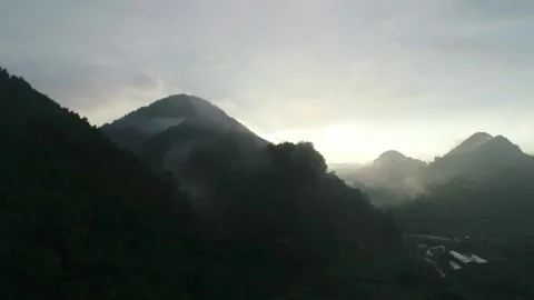 Sunlight Breaking Through Mist Over Lush Green Mountain Ranges at Dawn Vídeos de archivo 335461659