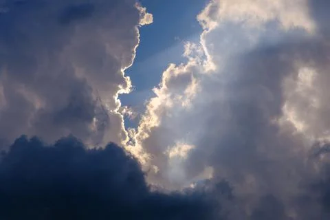Sunlight breaking through white and dark clouds in the blue sky Photos