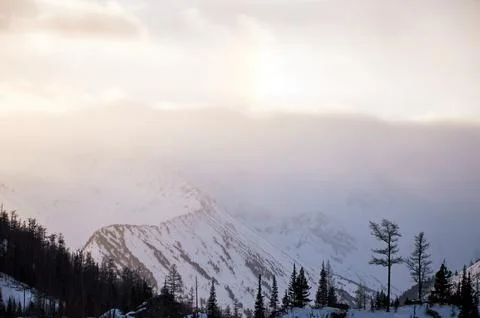 Sunlight breaks through clouds above snowcovered mountains. Foto stock