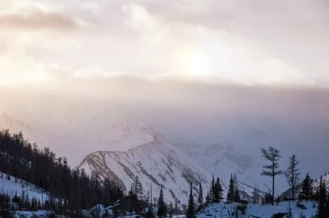 Sunlight breaks through clouds above snowcovered mountains. Foto stock