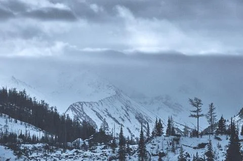 Sunlight breaks through clouds above snowcovered mountains. Foto stock