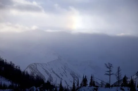 Sunlight breaks through clouds above snowcovered mountains. Foto stock