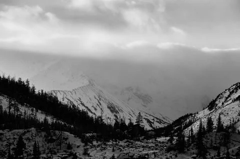 Sunlight breaks through clouds above snowcovered mountains. Fotos de archivo