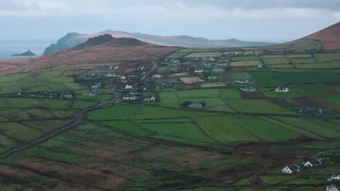 Sunlight breaks through clouds to light cliffs beyond circling green fields Stock Footage 328471284