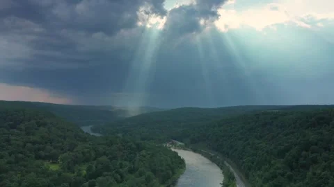 Sunlight breaks through clouds over river valley landscape Stock Footage 320304519