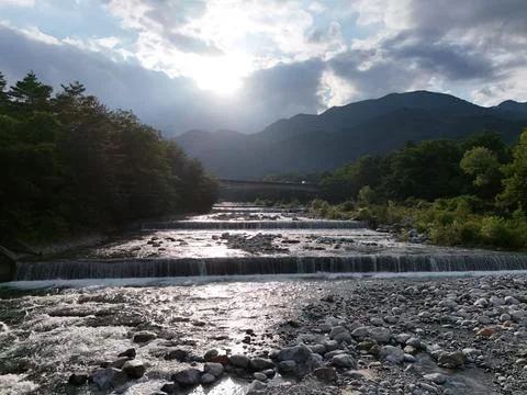 Sunlight breaks through clouds over a flowing river Fotos Stock