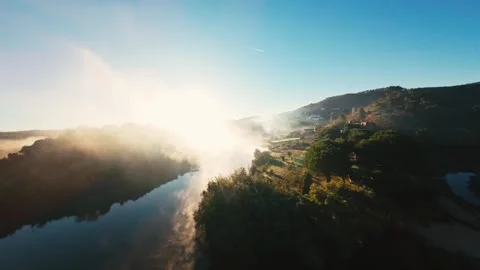 Sunlight breaks through fog over tranquil river and green hills Stock Footage 342270322