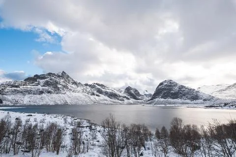 Sunlight breaks through heavy clouds over the snowy fjords near Sund, Lofot.. Foto stock