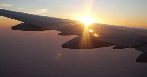 Sunlight bursting from behind airliner wing during flight turn at sunset Vidéo 341104355