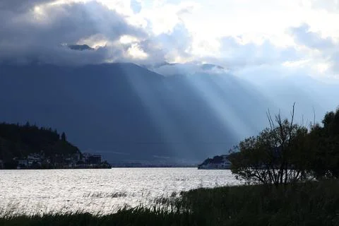 Sunlight casting dramatic shadows across erhai lake, revealing scenic landscape Stock Photos