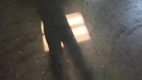 Sunlight casting a geometric window frame shadow on a textured concrete floor Stock Footage 332500796