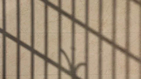 Sunlight casting moving window shadows on a beige marble wall surface Stock Footage 347038614