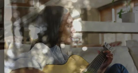 Sunlight casting patterns while woman pressing chords, strumming guitar and Stock Footage 311949084