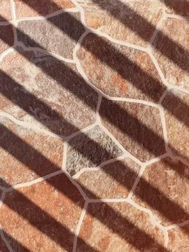 Sunlight casting shadows on decorative stone tile floor Stock-Fotos