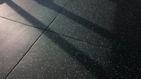 Sunlight is casting shadows diagonally across the dark rubber flooring tiles. Stock-Footage 335119851