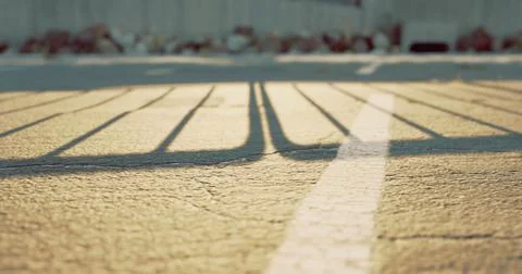 Sunlight casting shadows on pavement in an empty parking lot during sunset Stock Illustration