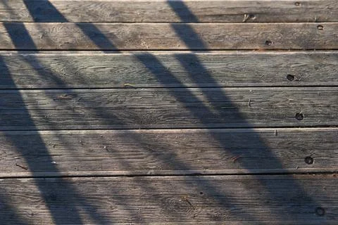 Sunlight casting shadows on weathered wooden deck, stairs in the park Stock Photos