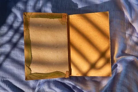 Sunlight casts dramatic shadow across open pages, sharp linear patterns, warm Stock Photos