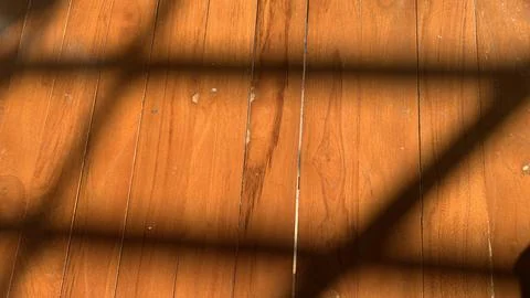 Sunlight casts geometric window shadows across polished wooden Fotos Stock