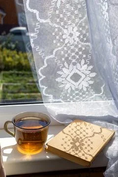 Sunlight casts intricate patterns through lace curtains, illuminating a warm  Stock Photos