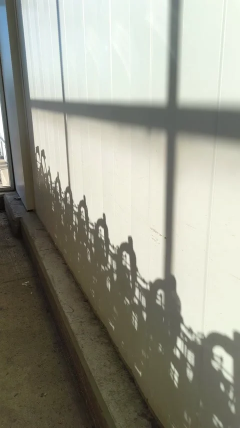 Sunlight casts intricate sunbeam dark moving shadow patterns of a city skyline Stockbeeldmateriaal 318610490