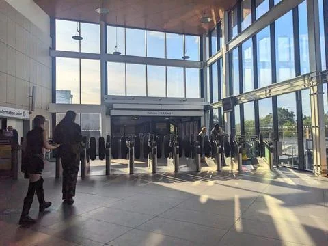 Sunlight casts long shadows as passengers walk through the ticket barriers at Stock Photos