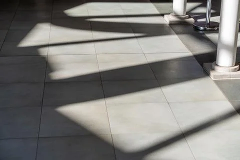 Sunlight casts sharp, angular shadows across tiled floor Stock Photos