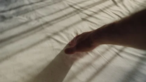 Sunlight casts striped shadows across a white bedsheet Видео 338098058