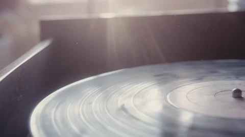 Sunlight catching dust particles dancing above spinning vinyl record Stock Footage 293698459