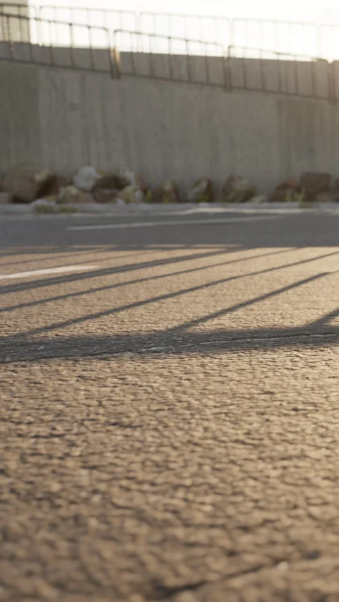 Sunlight creates shadow patterns on a road during late afternoon Stock Footage 338381471