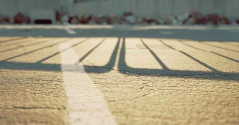 Sunlight creating long shadows across a pavement in an urban setting Stock Illustration
