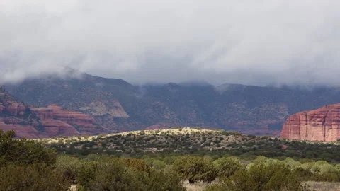 Sunlight dances as gray clouds flow over the desert outside of Sedona, Arizona Stock Footage 146668792