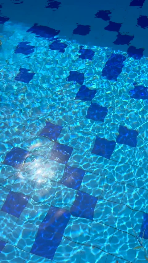 Sunlight dances on shimmering tiles beneath clear water in vibrant summer pool Stock Footage 337016766