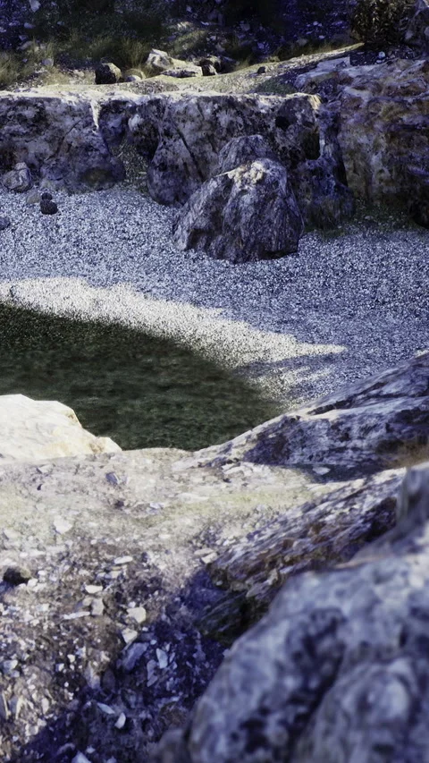 Sunlight dances on tranquil waters at a hidden rocky pool in nature Stock Footage 331367901