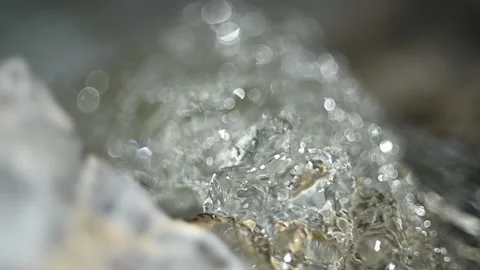 Sunlight effects of clear water flowing over mountain river rocks (slow motion) Video stock 212737902